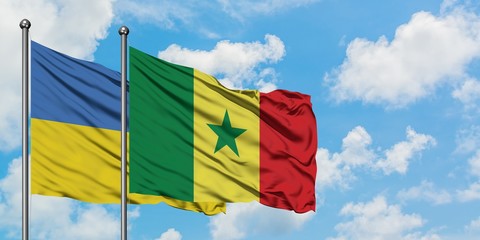 Ukraine and Senegal flag waving in the wind against white cloudy blue sky together. Diplomacy concept, international relations.