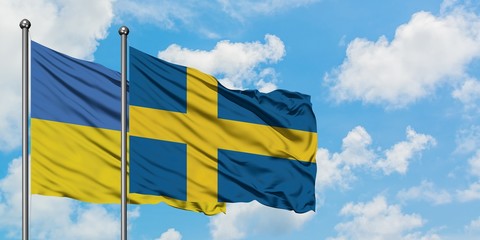 Ukraine and Sweden flag waving in the wind against white cloudy blue sky together. Diplomacy concept, international relations.