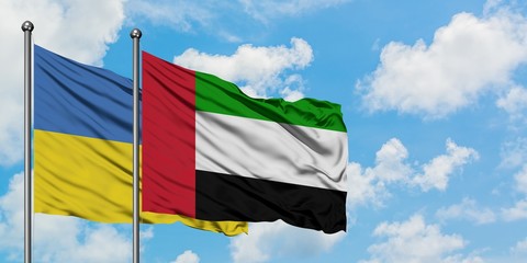 Ukraine and United Arab Emirates flag waving in the wind against white cloudy blue sky together. Diplomacy concept, international relations.