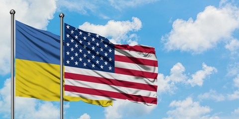 Ukraine and United States flag waving in the wind against white cloudy blue sky together. Diplomacy concept, international relations.