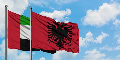 United Arab Emirates and Albania flag waving in the wind against white cloudy blue sky together. Diplomacy concept, international relations.