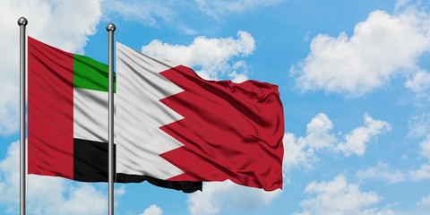 United Arab Emirates and Bahrain flag waving in the wind against white cloudy blue sky together. Diplomacy concept, international relations.