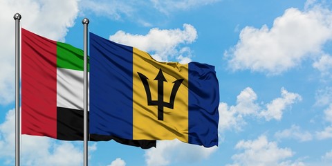 United Arab Emirates and Barbados flag waving in the wind against white cloudy blue sky together. Diplomacy concept, international relations.