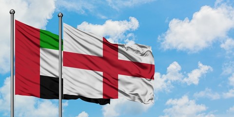 United Arab Emirates and England flag waving in the wind against white cloudy blue sky together. Diplomacy concept, international relations.