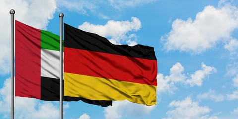 United Arab Emirates and Germany flag waving in the wind against white cloudy blue sky together. Diplomacy concept, international relations.