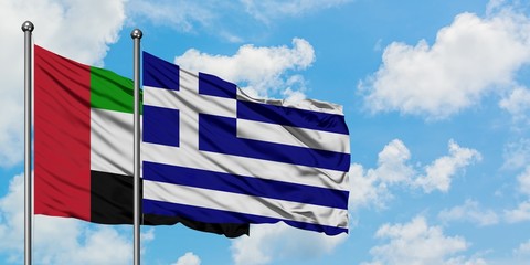 United Arab Emirates and Greece flag waving in the wind against white cloudy blue sky together. Diplomacy concept, international relations.