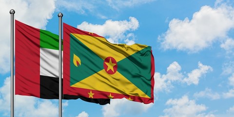 United Arab Emirates and Grenada flag waving in the wind against white cloudy blue sky together. Diplomacy concept, international relations.