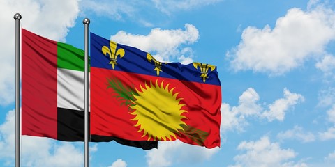 United Arab Emirates and Guadeloupe flag waving in the wind against white cloudy blue sky together. Diplomacy concept, international relations.