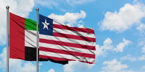 United Arab Emirates and Liberia flag waving in the wind against white cloudy blue sky together. Diplomacy concept, international relations.