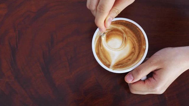 hands holding cup of latte coffee on wooden table with copy space , caffeine concept.