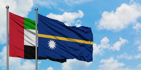 United Arab Emirates and Nauru flag waving in the wind against white cloudy blue sky together....