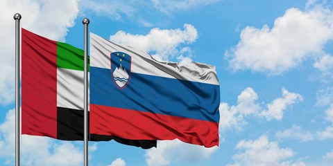 United Arab Emirates and Slovenia flag waving in the wind against white cloudy blue sky together. Diplomacy concept, international relations.