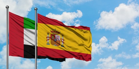 United Arab Emirates and Spain flag waving in the wind against white cloudy blue sky together. Diplomacy concept, international relations.