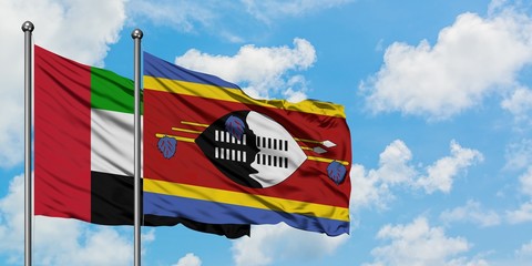 United Arab Emirates and Swaziland flag waving in the wind against white cloudy blue sky together....
