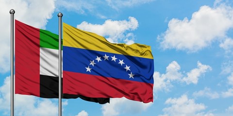 United Arab Emirates and Venezuela flag waving in the wind against white cloudy blue sky together. Diplomacy concept, international relations.