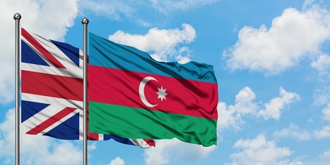 United Kingdom and Azerbaijan flag waving in the wind against white cloudy blue sky together. Diplomacy concept, international relations.