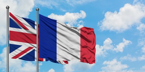 United Kingdom and France flag waving in the wind against white cloudy blue sky together. Diplomacy...