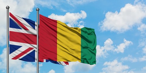United Kingdom and Guinea flag waving in the wind against white cloudy blue sky together. Diplomacy concept, international relations.