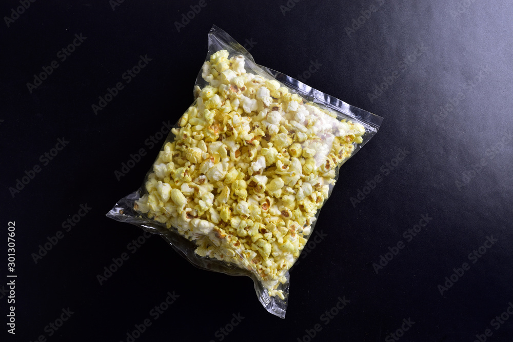 Wall mural plastic packet of pop corn on black background - Wall murals