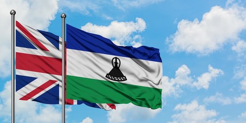 United Kingdom and Lesotho flag waving in the wind against white cloudy blue sky together. Diplomacy concept, international relations.