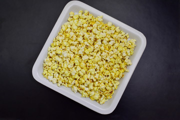 popcorn in white tray on black background