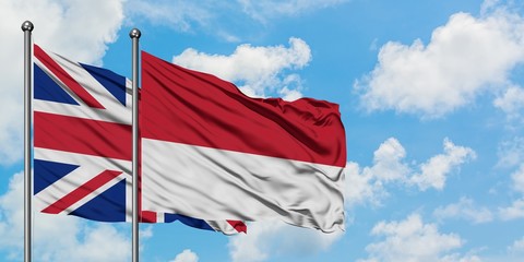 United Kingdom and Monaco flag waving in the wind against white cloudy blue sky together. Diplomacy concept, international relations.