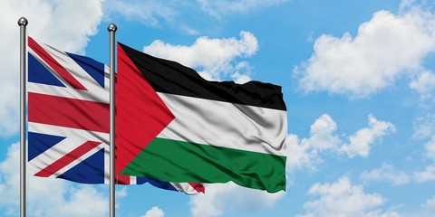 United Kingdom and Palestine flag waving in the wind against white cloudy blue sky together. Diplomacy concept, international relations.