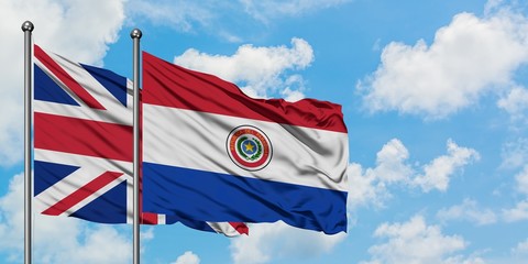 United Kingdom and Paraguay flag waving in the wind against white cloudy blue sky together. Diplomacy concept, international relations.