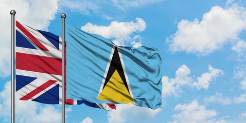 United Kingdom and Saint Lucia flag waving in the wind against white cloudy blue sky together. Diplomacy concept, international relations.