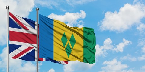 United Kingdom and Saint Vincent And The Grenadines flag waving in the wind against white cloudy...