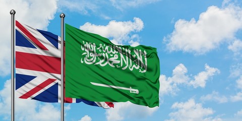 United Kingdom and Saudi Arabia flag waving in the wind against white cloudy blue sky together. Diplomacy concept, international relations.