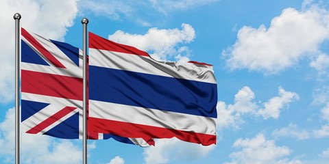 United Kingdom and Thailand flag waving in the wind against white cloudy blue sky together. Diplomacy concept, international relations.