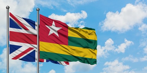United Kingdom and Togo flag waving in the wind against white cloudy blue sky together. Diplomacy concept, international relations.