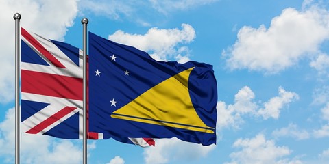 United Kingdom and Tokelau flag waving in the wind against white cloudy blue sky together. Diplomacy concept, international relations.