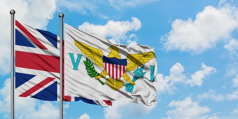 United Kingdom and United States Virgin Islands flag waving in the wind against white cloudy blue sky together. Diplomacy concept, international relations.