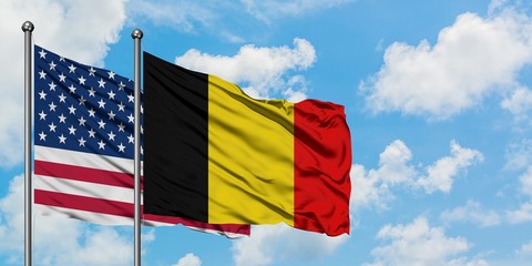 United States and Belgium flag waving in the wind against white cloudy blue sky together. Diplomacy...
