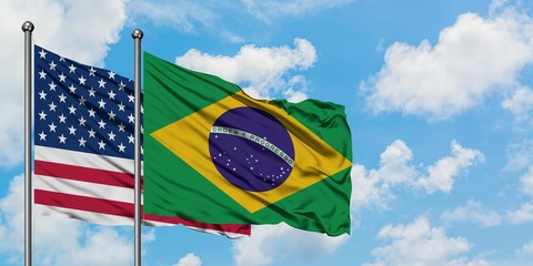 United States and Brazil flag waving in the wind against white cloudy blue sky together. Diplomacy concept, international relations.