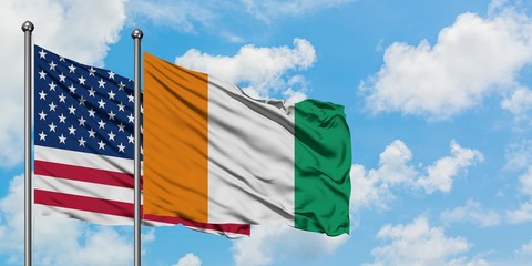 United States and Cote D'Ivoire flag waving in the wind against white cloudy blue sky together. Diplomacy concept, international relations.