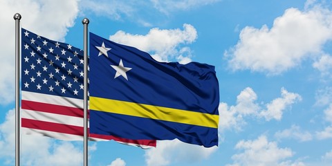 United States and Curacao flag waving in the wind against white cloudy blue sky together. Diplomacy concept, international relations.