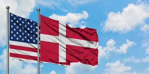 United States and Denmark flag waving in the wind against white cloudy blue sky together. Diplomacy concept, international relations.