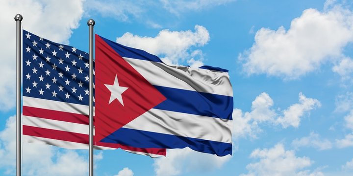 United States and Cuba flag waving in the wind against white cloudy blue sky together. Diplomacy concept, international relations.