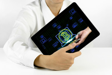 Businessman holding a tablet with bitcoin symbol and laptop icons on binary background