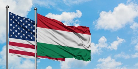 United States and Hungary flag waving in the wind against white cloudy blue sky together. Diplomacy concept, international relations.