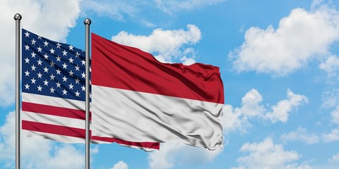 United States and Indonesia flag waving in the wind against white cloudy blue sky together....