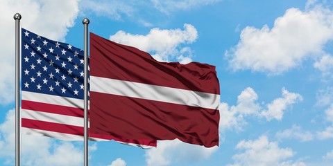 United States and Latvia flag waving in the wind against white cloudy blue sky together. Diplomacy concept, international relations.