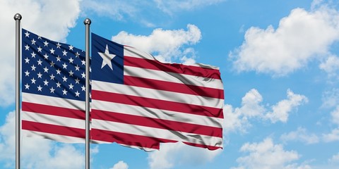 United States and Liberia flag waving in the wind against white cloudy blue sky together. Diplomacy concept, international relations.