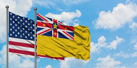 United States and Niue flag waving in the wind against white cloudy blue sky together. Diplomacy concept, international relations.