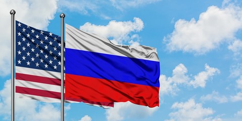 United States and Russia flag waving in the wind against white cloudy blue sky together. Diplomacy concept, international relations.