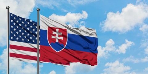 United States and Slovakia flag waving in the wind against white cloudy blue sky together. Diplomacy concept, international relations.