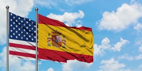 United States and Spain flag waving in the wind against white cloudy blue sky together. Diplomacy concept, international relations.